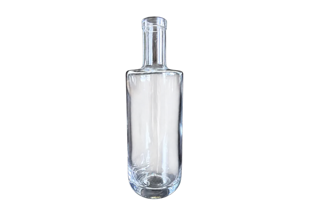 Clear empty cylindrical glass liquor bottle with a long neck and stopper on a dark background