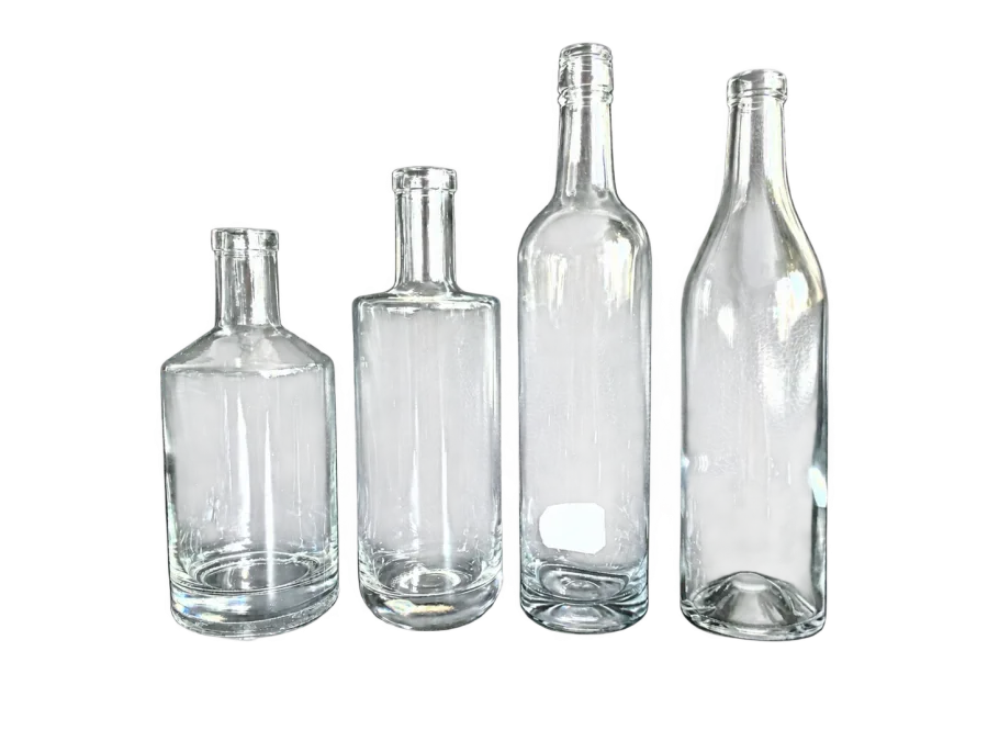 Four clear glass bottles with different body shapes displayed on a dark surface