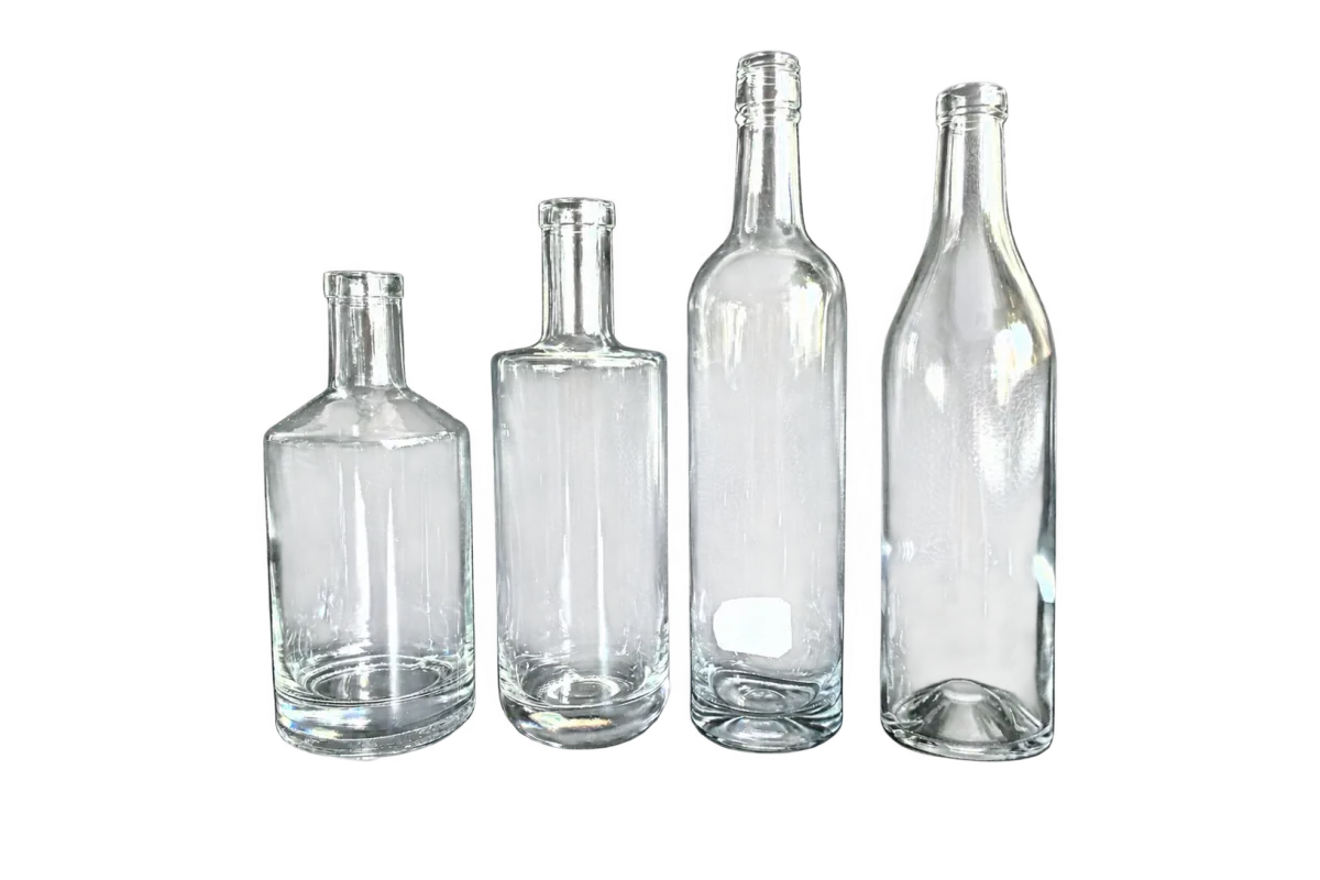 Four clear glass bottles with different body shapes displayed on a dark surface