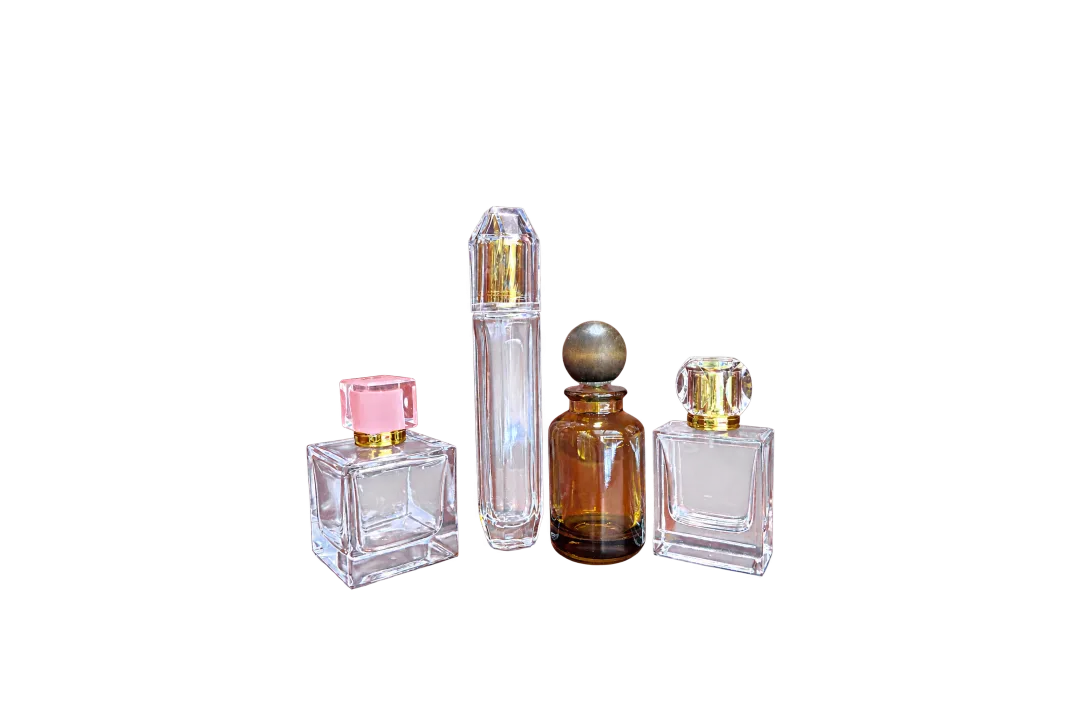 Four decorative glass fragrance bottles with faceted and spherical caps arranged against a red backdrop.