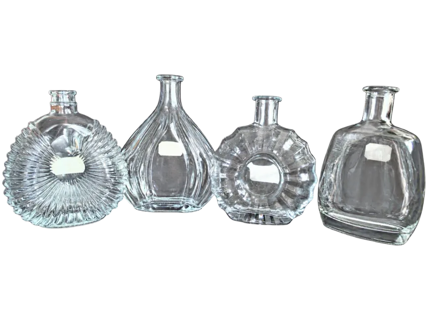 Four clear decorative glass bottles with faceted and fluted designs arranged on a dark leather seat