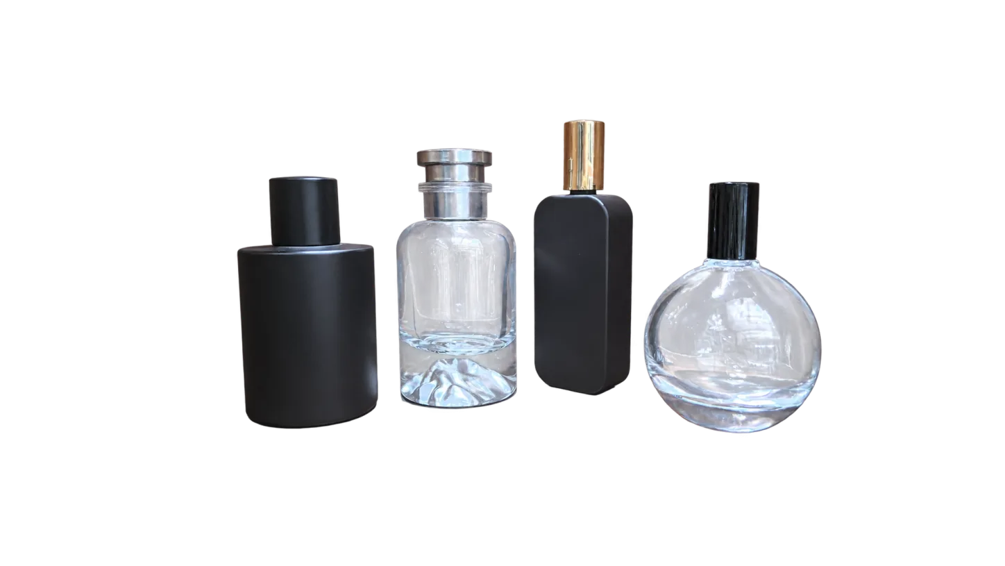 Four unlabelled fragrance-style bottles in black and clear finishes displayed on a wooden surface.