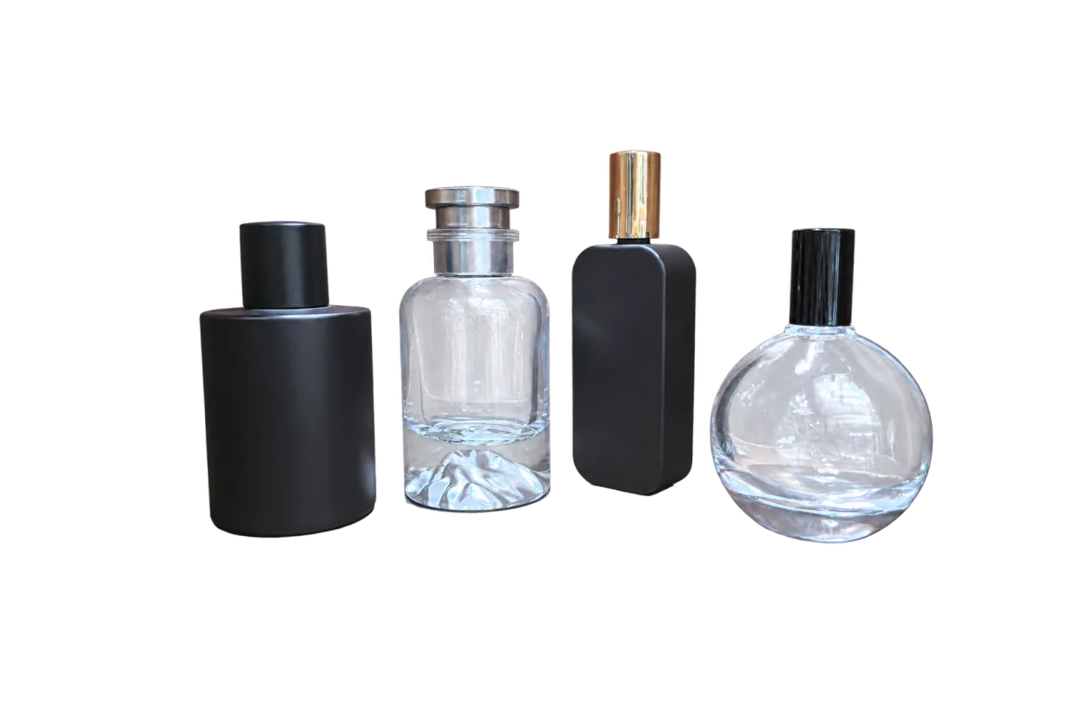 Four unlabelled fragrance-style bottles in black and clear finishes displayed on a wooden surface.