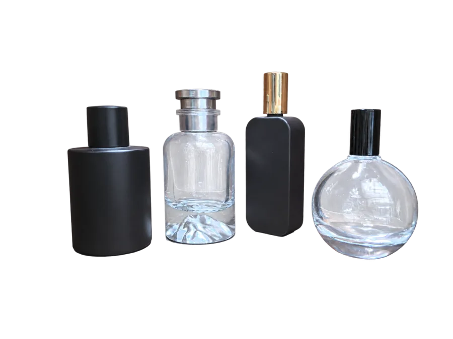 Four unlabelled fragrance-style bottles in black and clear finishes displayed on a wooden surface.