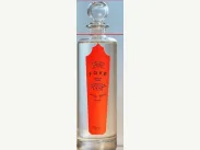 Photograph of a tall clear bottle with a spherical glass stopper and red vertical label.