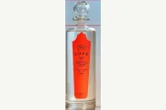 Photograph of a tall clear bottle with a spherical glass stopper and red vertical label.