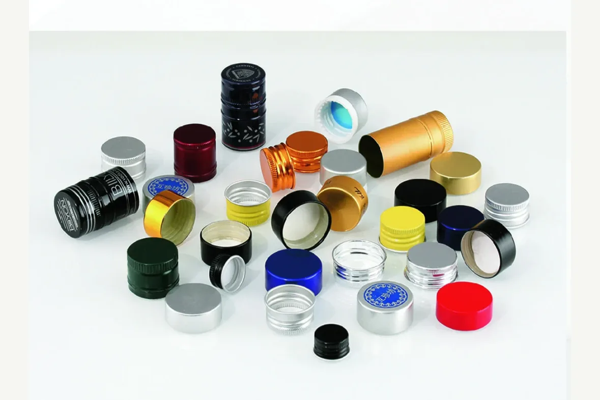 A group of metallic and colored caps and closure components arranged on a pale background.