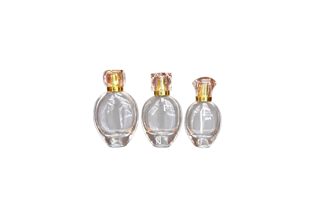 Three clear round bottles with faceted caps and gold-colored neck collars displayed on a wooden surface