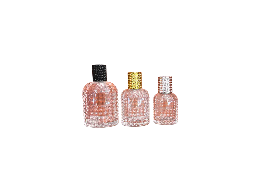 Three transparent faceted bottles with black, gold, and silver textured caps on an orange surface